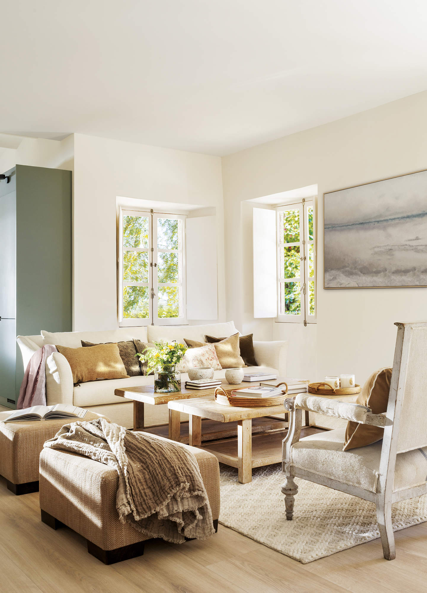 salón con sofá blanco con cojines mostaza, butaca blanca, alfombra blanca y suelo de madera